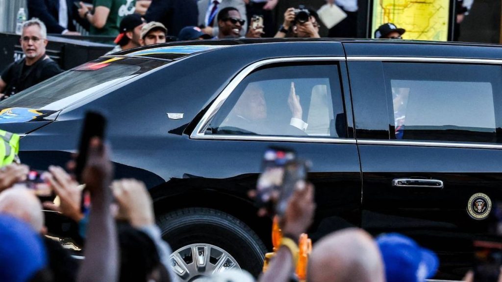 0 An official vehicle possibly a limousine is surrounded by a crowd of individuals some of whom are taking photographs