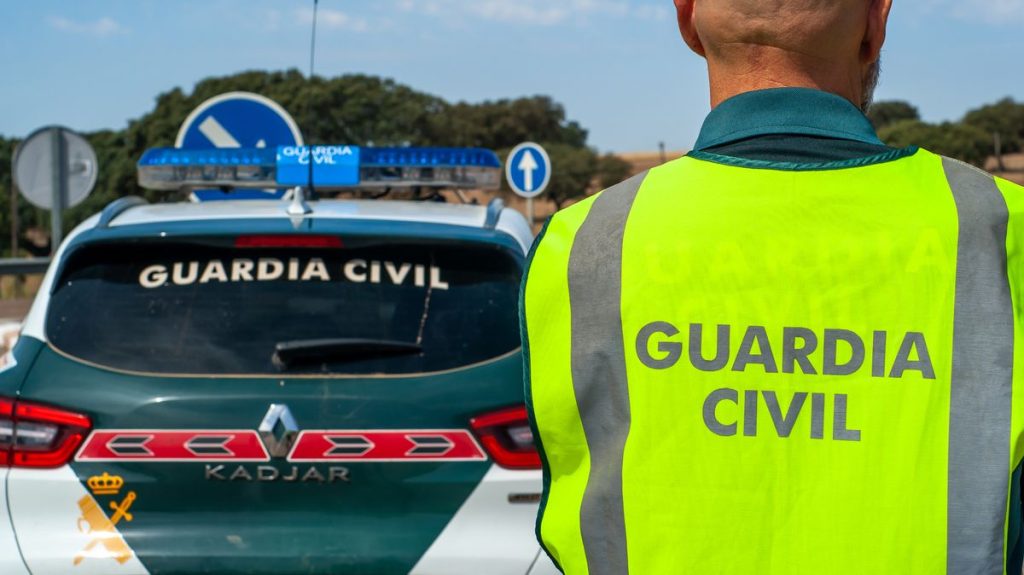 1 Civil guard agent equipped with his reflective vest next to the patrol car on a road