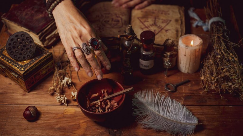 0 Female witch making potion on dark background magic bottles with potions and candles on table of al