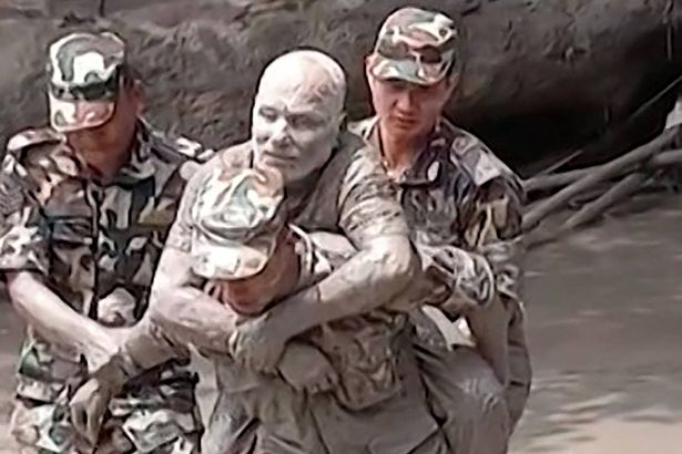 0 A man is pulled from the mud by soldiers