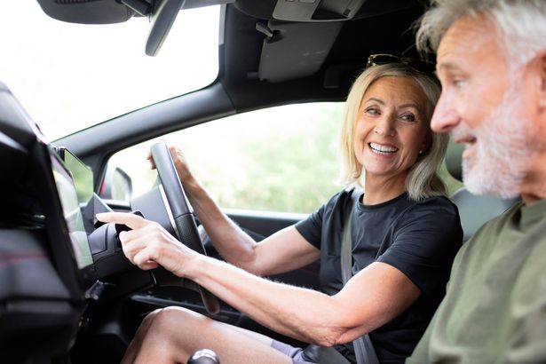 2 Smiling mature female car driver setting the gps navigation system