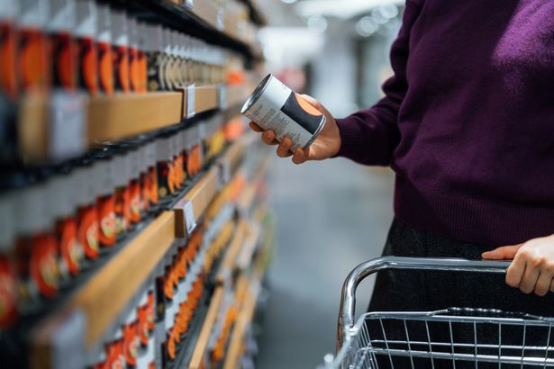 2 Cropped shot of young woman pushing a shopping cart grocery shopping in supermarket She is holding