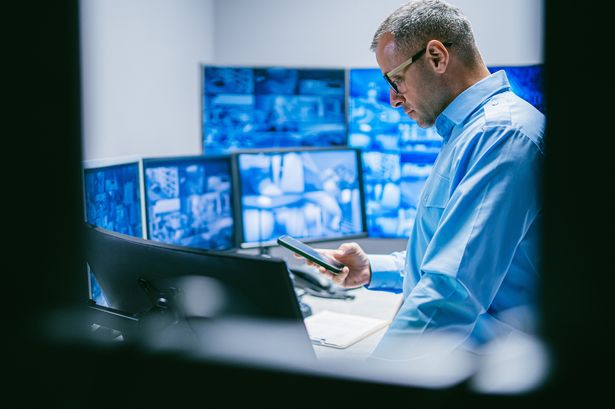 2 Security Male Operator Reviewing Data in Control Room with Technology