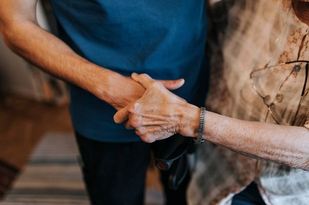 0 Midsection of male healthcare worker holding hand of senior woman at home